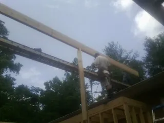 Carpenter setting a ridge beam over a new addition frame — Ice Dam Removal by Roofing Brothers in Alloy