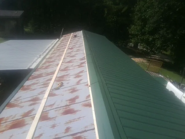 Old rusted panels beside newly installed green metal roofing — Wind Damage Roof Repair by Roofing Brothers in Alloy