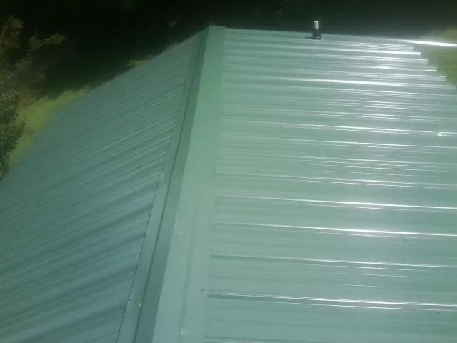 New green metal panels meeting at the ridge of a roof — Flat Roof Repair work by our crew in Alloy