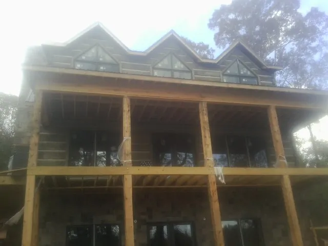 Dormers and porch framing on a large log home under construction — Roof Coating work by our crew in Alloy