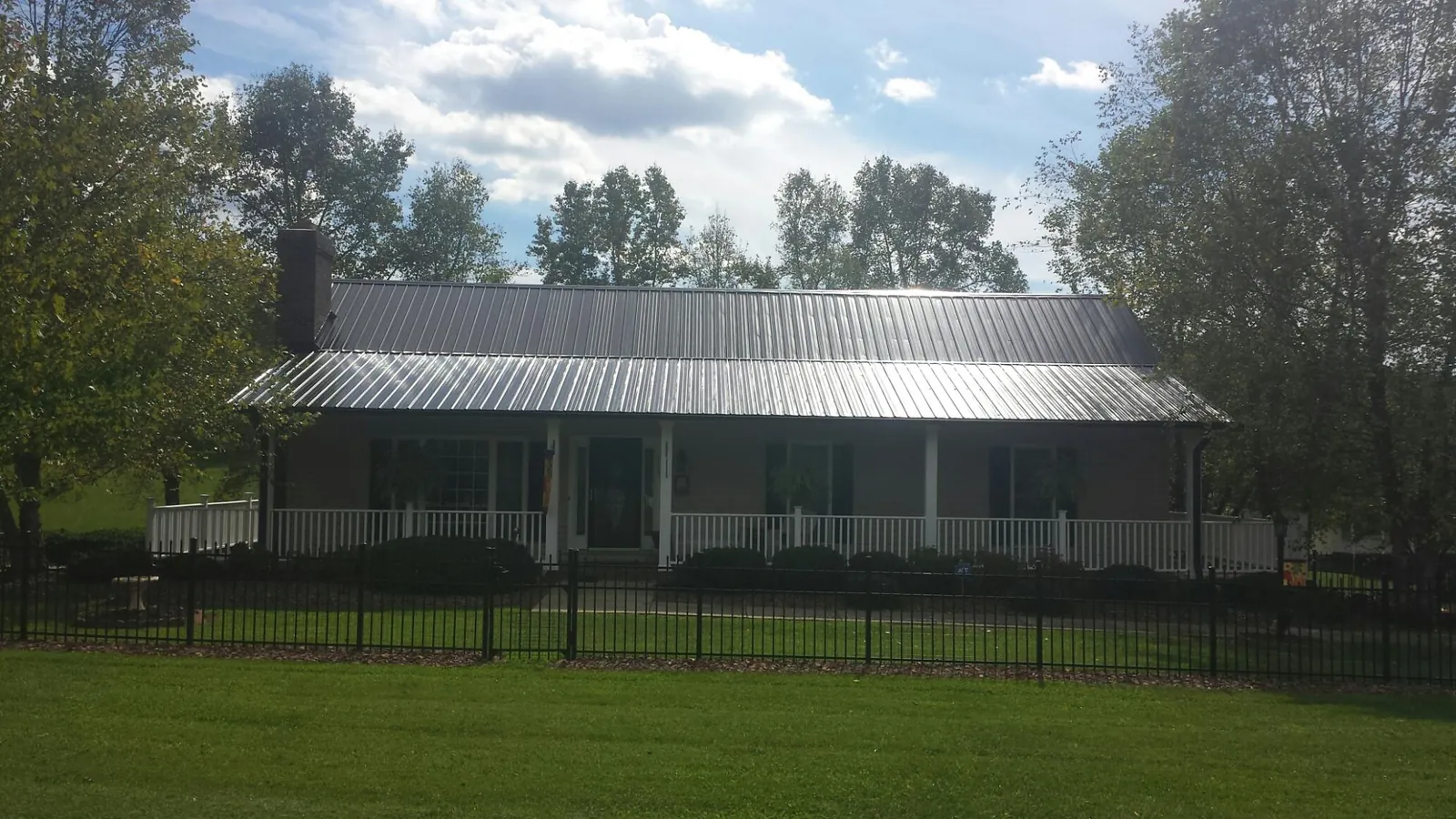 Gray metal roof on a brick ranch with a full width front porch — Gutter Guard Installation work by our crew in Alloy